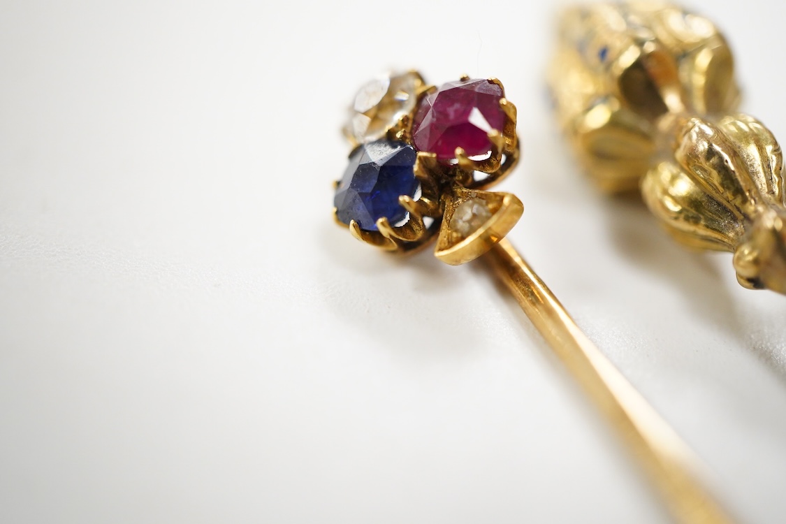 An early 20th century Viennese yellow metal, ruby, diamond and sapphire set 'clover' stick pin, 68mm, together with a yellow metal and blue enamel set stick pin.